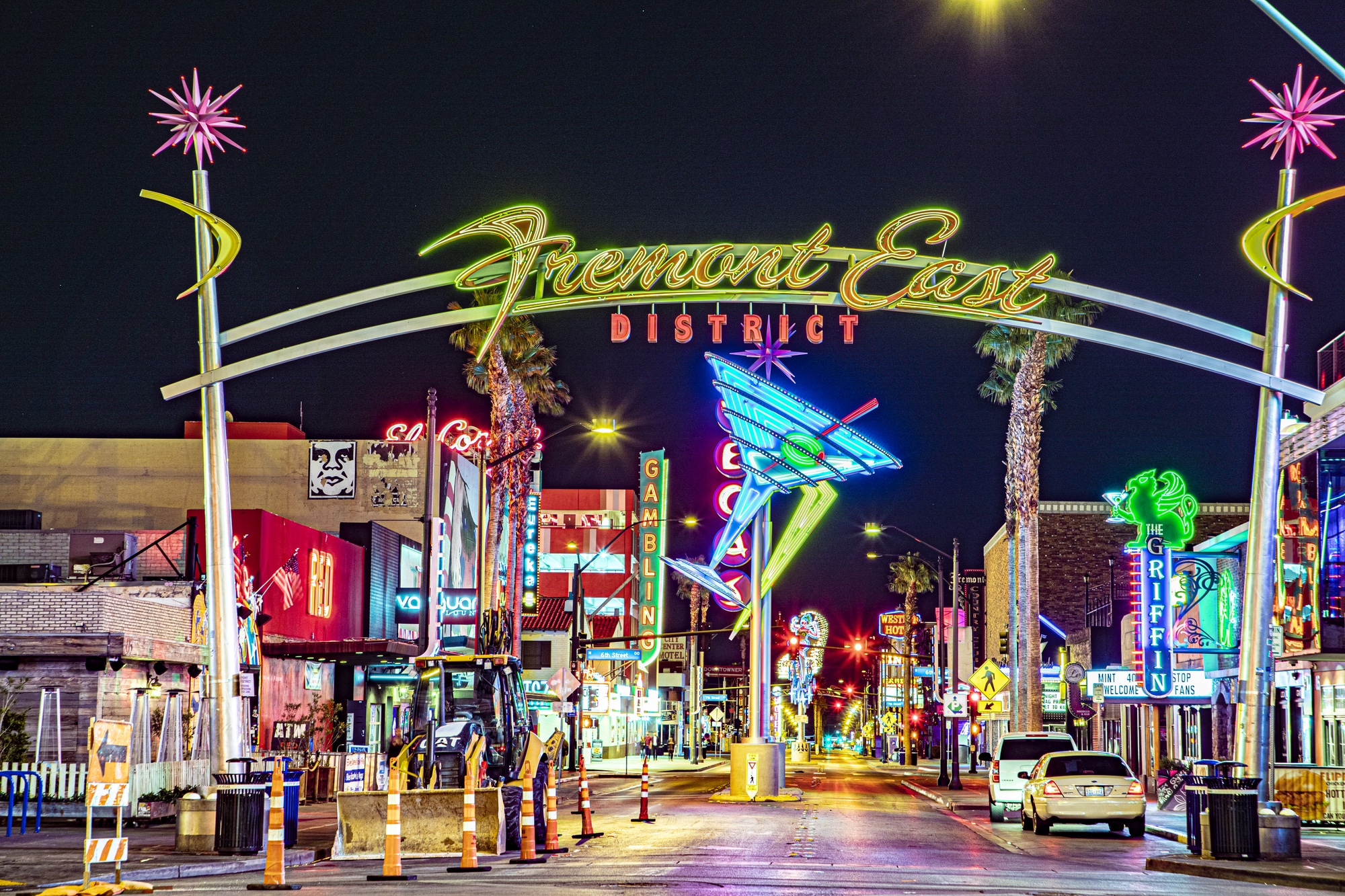 Arco iluminado do Fremont East District sobre uma rua com letreiros de neon à noite