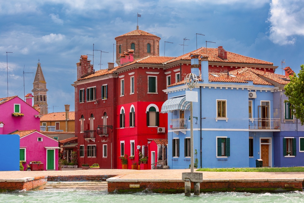 Casas coloridas ao longo de um canal em Burano com o campanário ao fundo