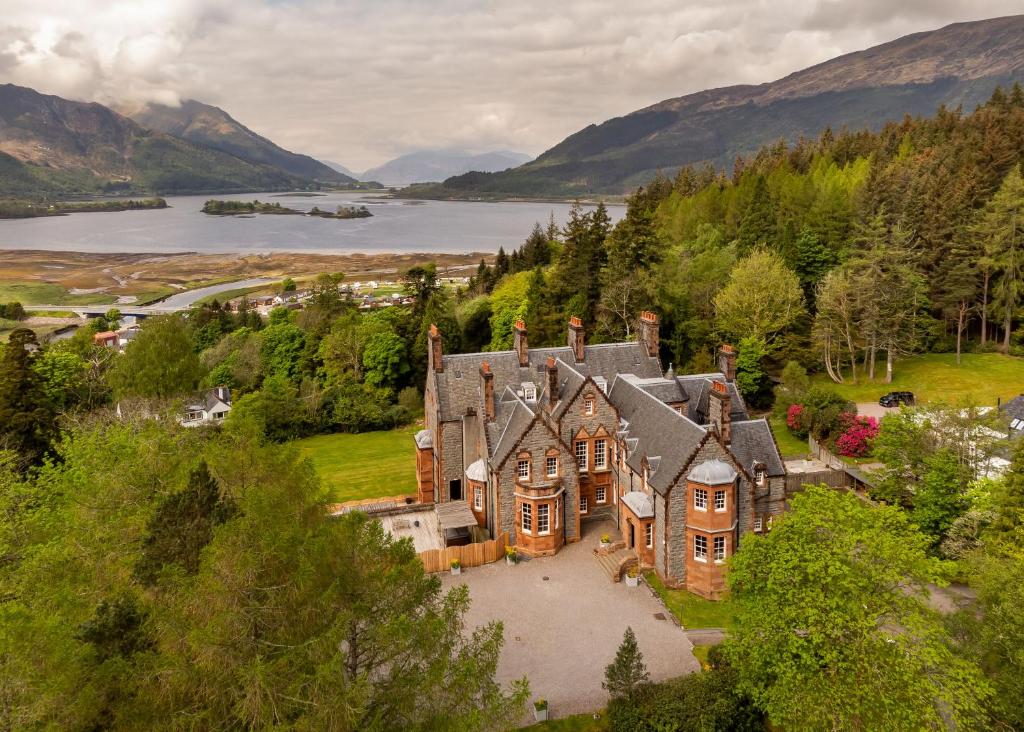 Glencoe House cercada de árvores com um lago e montanhas atrás
