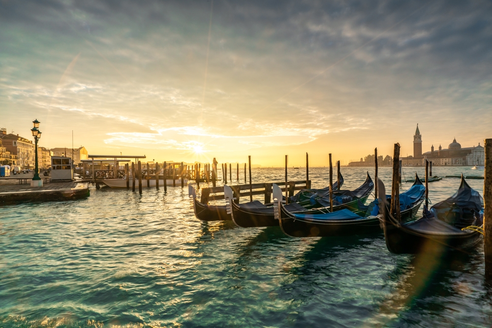 Gôndolas atracadas no cais em Veneza ao pôr do sol