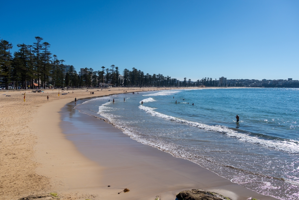 Manly Beach, em Sydney, com areia dourada e ondas azuis