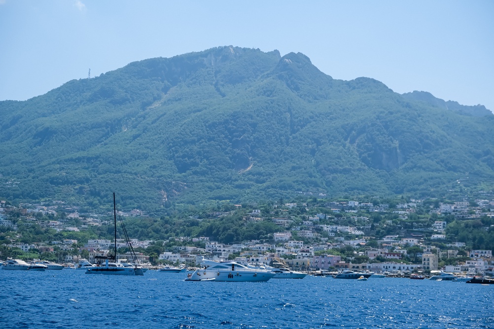 O monte Epomeo e uma cidade portuária em Ischia, com barcos ancorados em primeiro plano