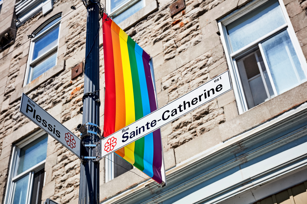 Placas da Rue Sainte-Catherine e da Rue Plessis com bandeira do arco-íris no Village, em Montreal