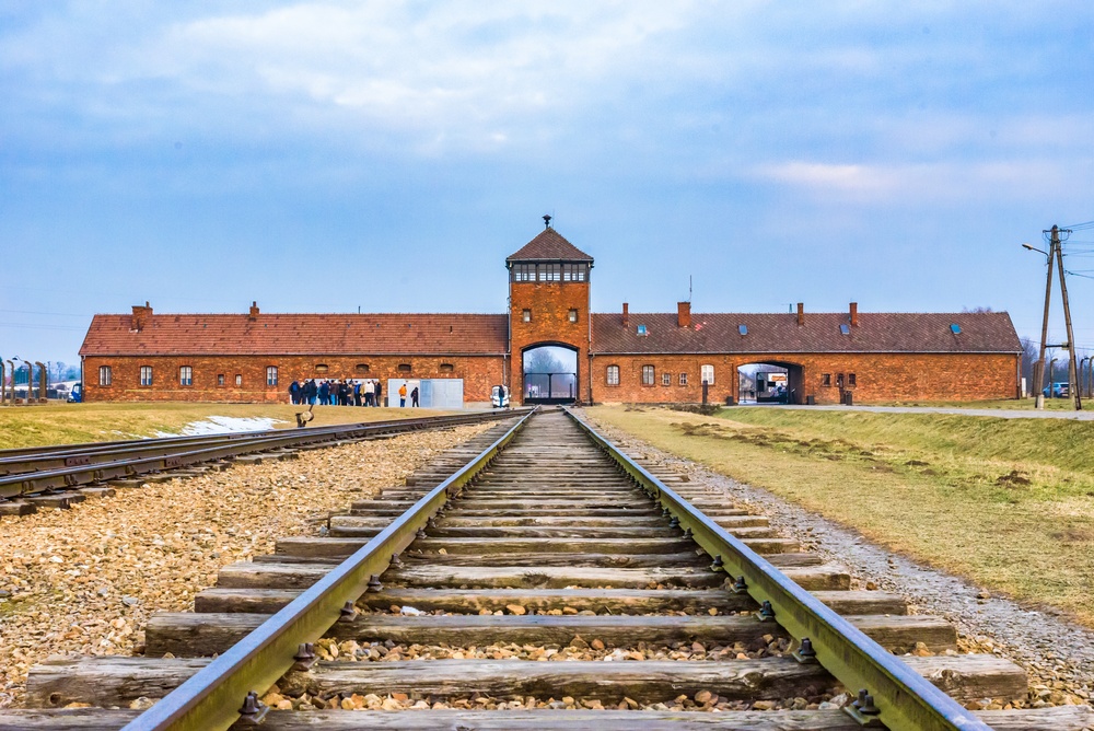 O portão de entrada e a linha férrea de Auschwitz-Birkenau vistos de dentro do campo