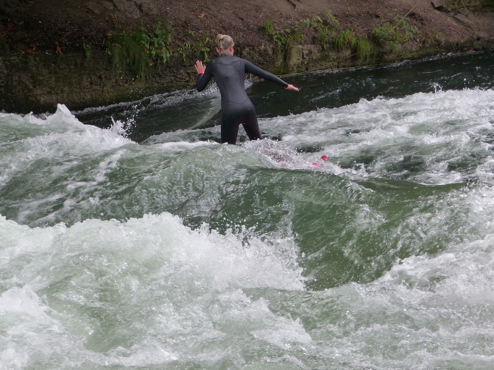 Um surfista na onda do Eisbach junto ao Englischer Garten em Munique