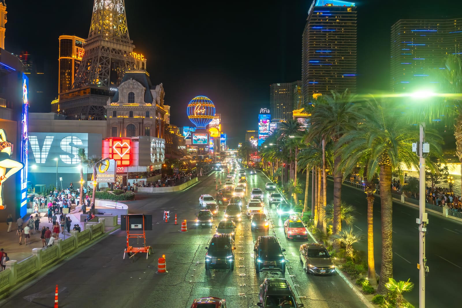 Trânsito, palmeiras e hotéis iluminados ao longo da Las Vegas Strip à noite